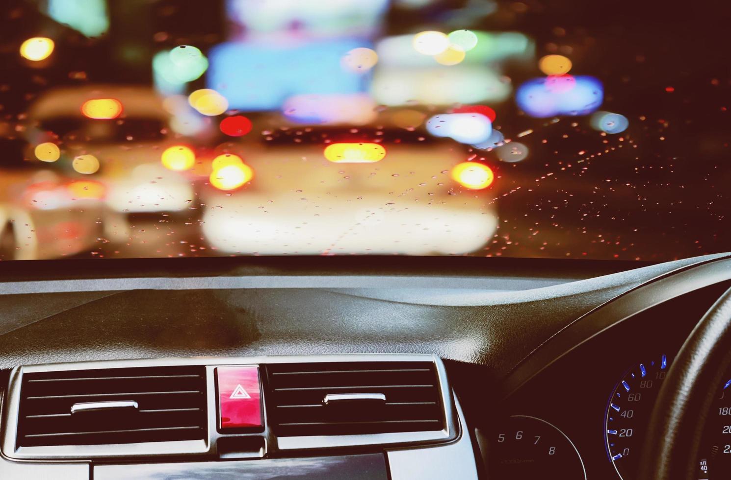vista frontale dell'auto che guarda dall'interno con una goccia di pioggia durante il crepuscolo sullo sfondo della strada foto