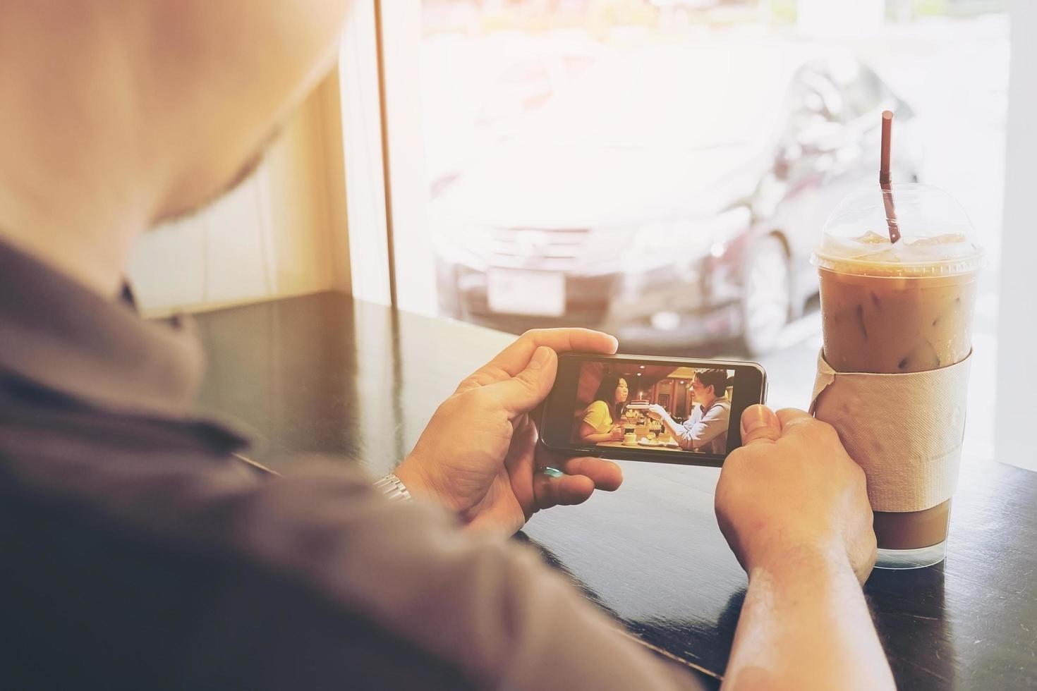 l'uomo sta usando il telefono cellulare mentre è seduto in una caffetteria foto