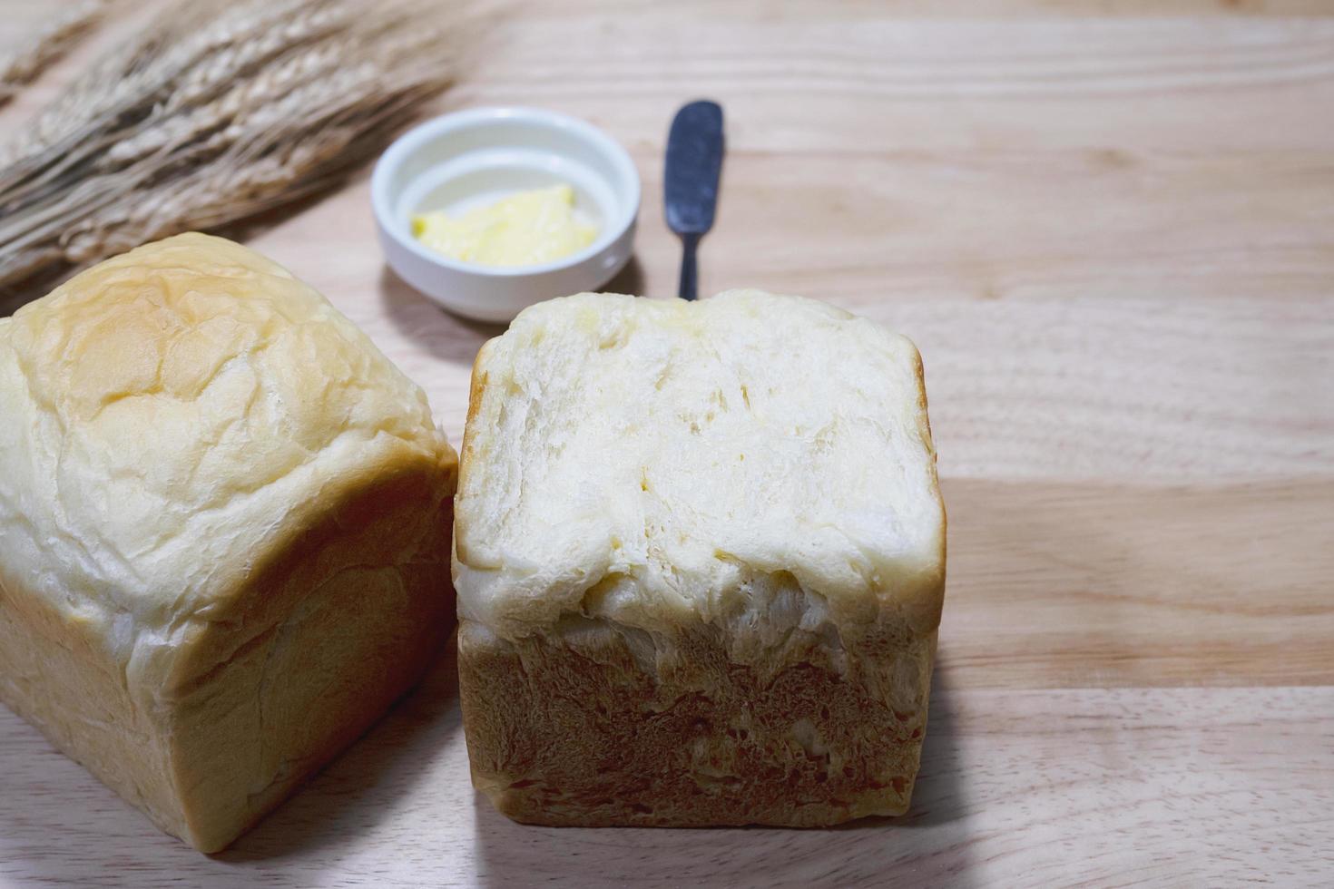 pane tostato con grano secco e burro su tavola di legno - concetto di sfondo per la colazione da forno foto