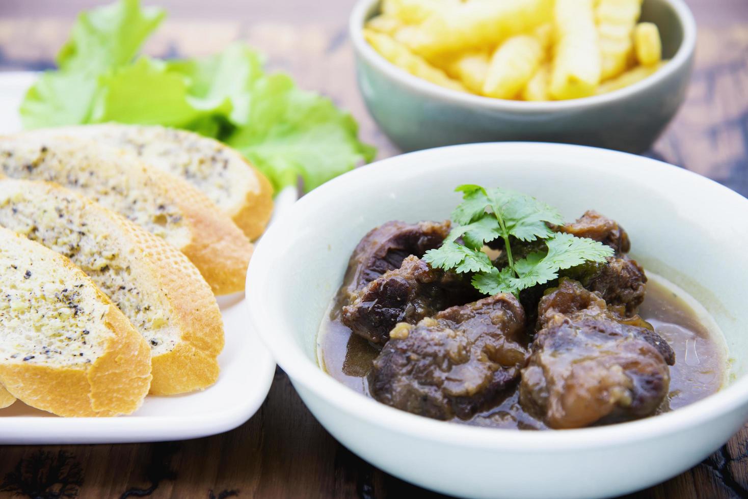 stufato di manzo e maiale con patatine fritte e altre ricette alimentari su tavola di legno, pasto pronto per il cibo che preparano il concetto foto