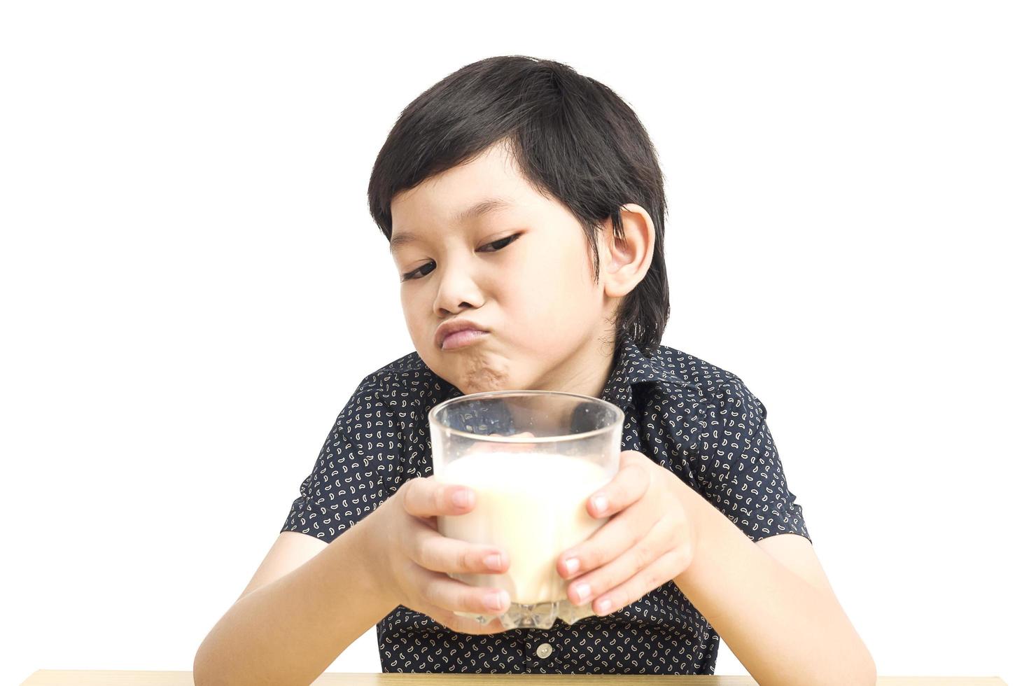 ragazzo asiatico sta mostrando antipatia per bere l'espressione del latte su sfondo bianco foto