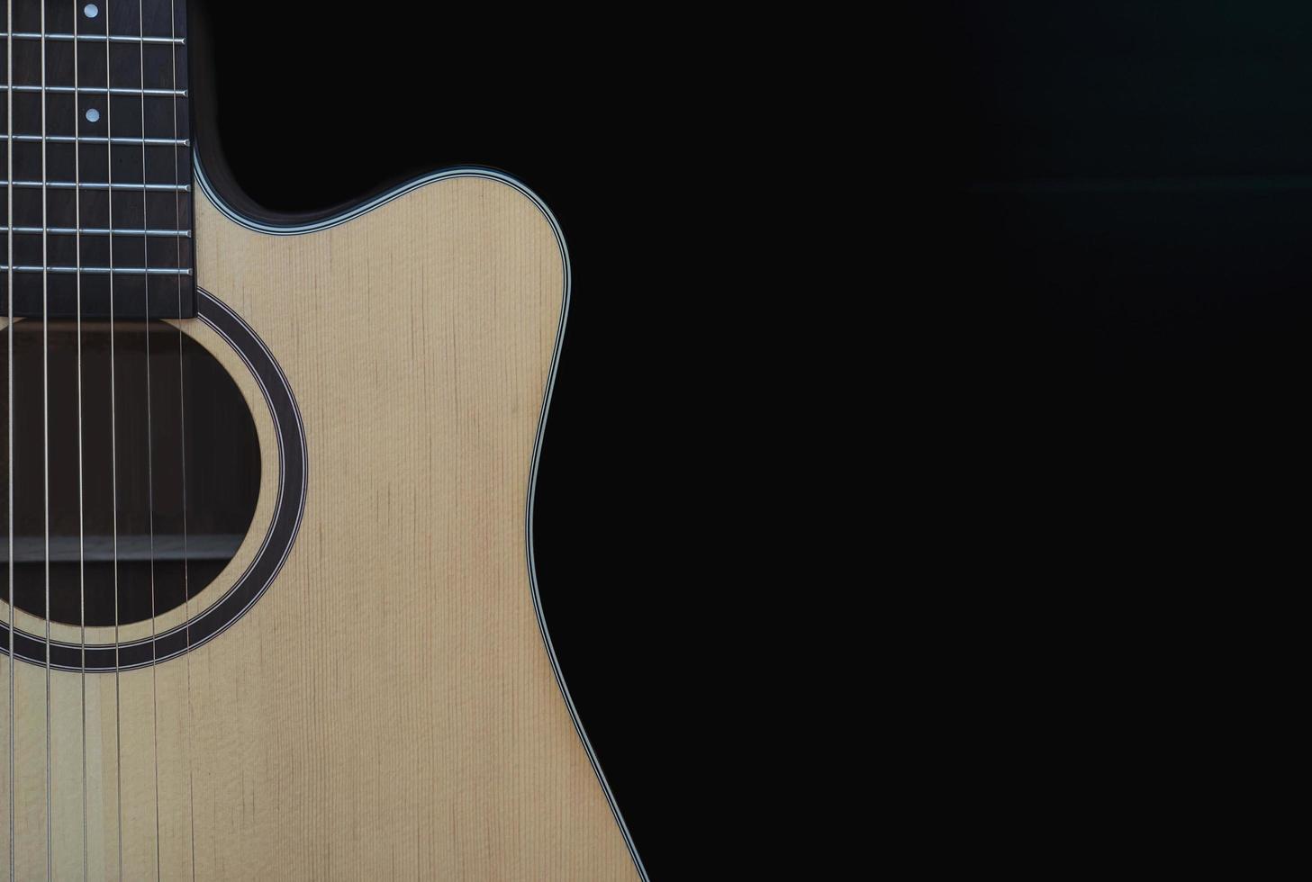 primo piano della chitarra acustica cutaway su sfondo nero foto