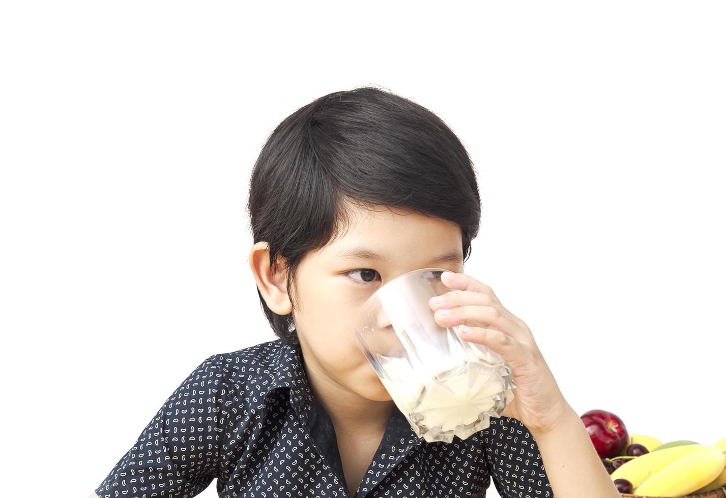 ragazzo asiatico sta bevendo un bicchiere di latte su sfondo bianco foto