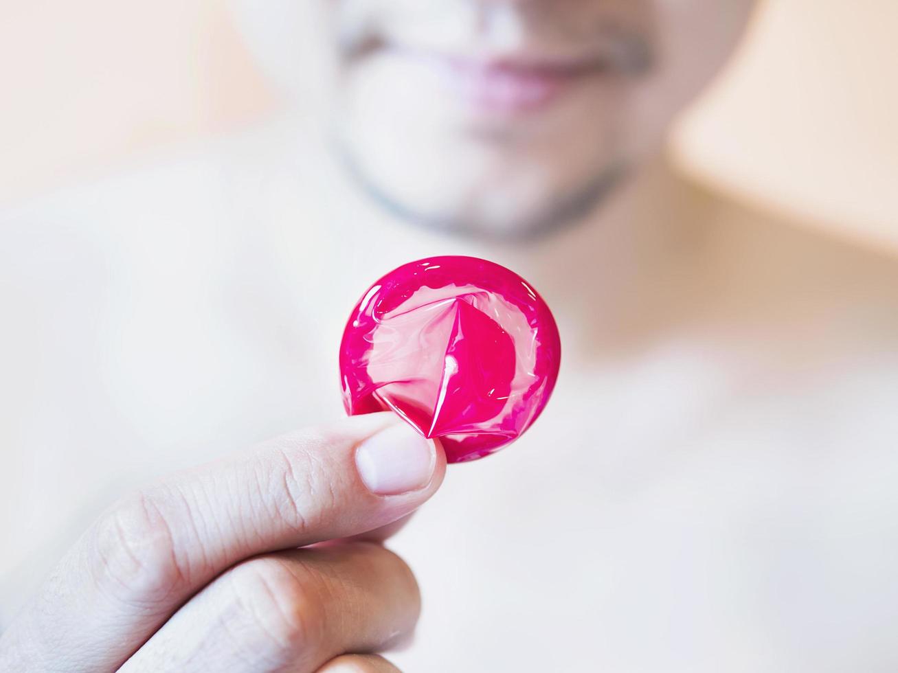 l'uomo sta mostrando il concetto di sesso sicuro con preservativo rosso foto