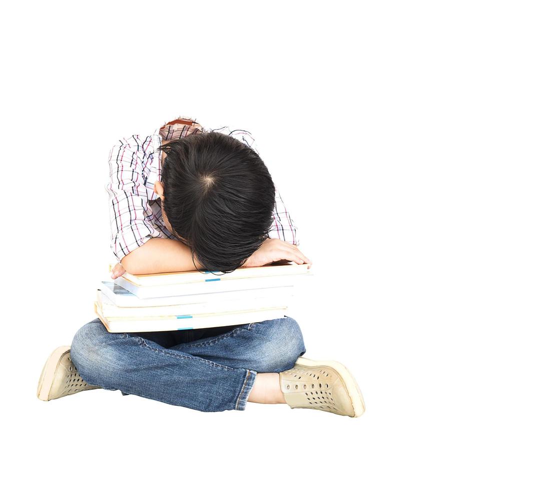 Il ragazzo asiatico di 7 anni sta dormendo con una pila di libri isolata sopra bianco. foto