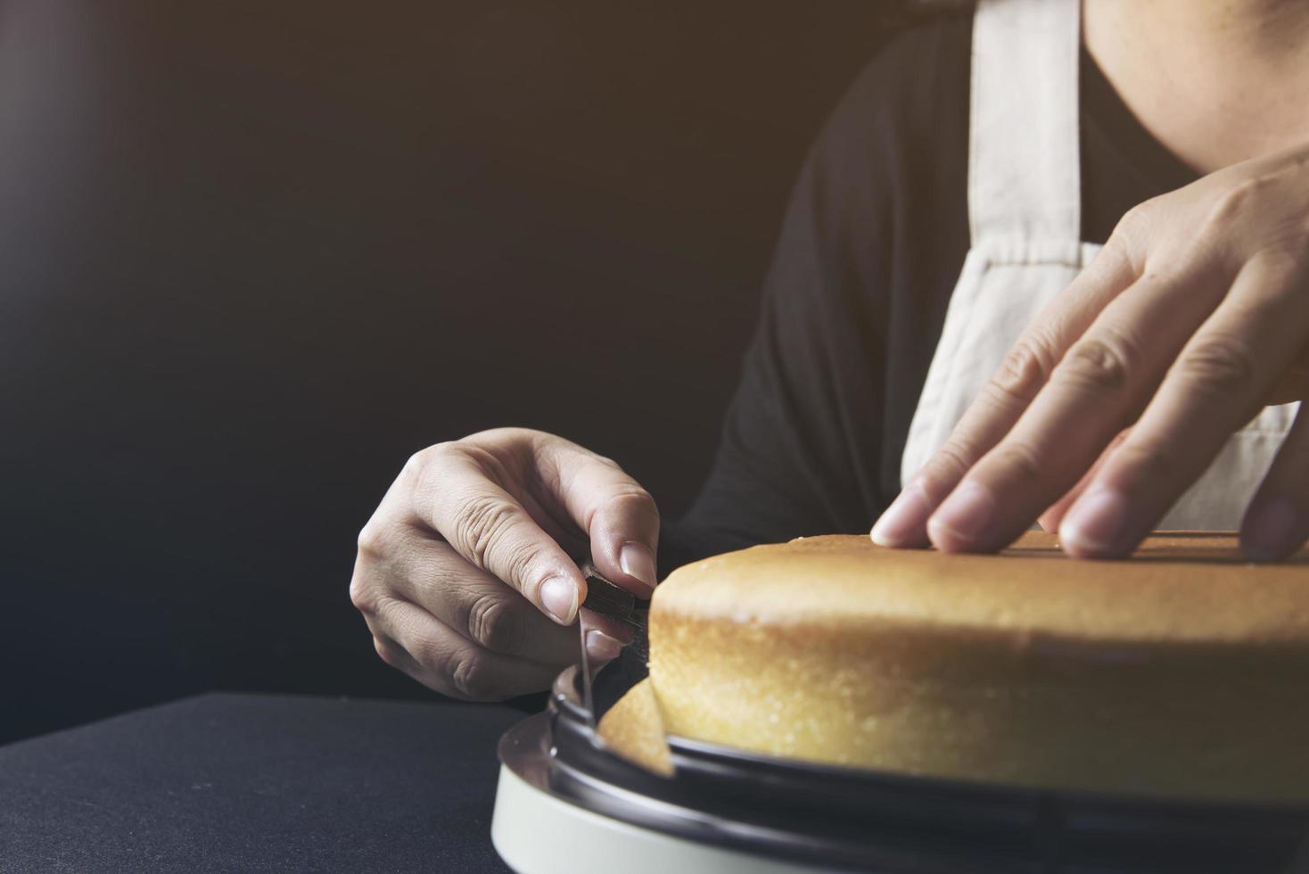 signora che fa la torta mettendo la crema con la spatola - concetto di cucina da forno fatto in casa foto