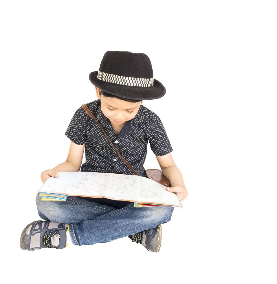 Il ragazzo asiatico di 7 anni è felicemente seduto e guarda una mappa mentre punta il dito indice isolato su bianco foto