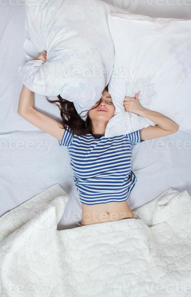 la ragazza dorme in un letto bianco a casa. giovane donna che dorme in indumenti da notte sulla biancheria bianca a letto a casa, vista dall'alto. foto