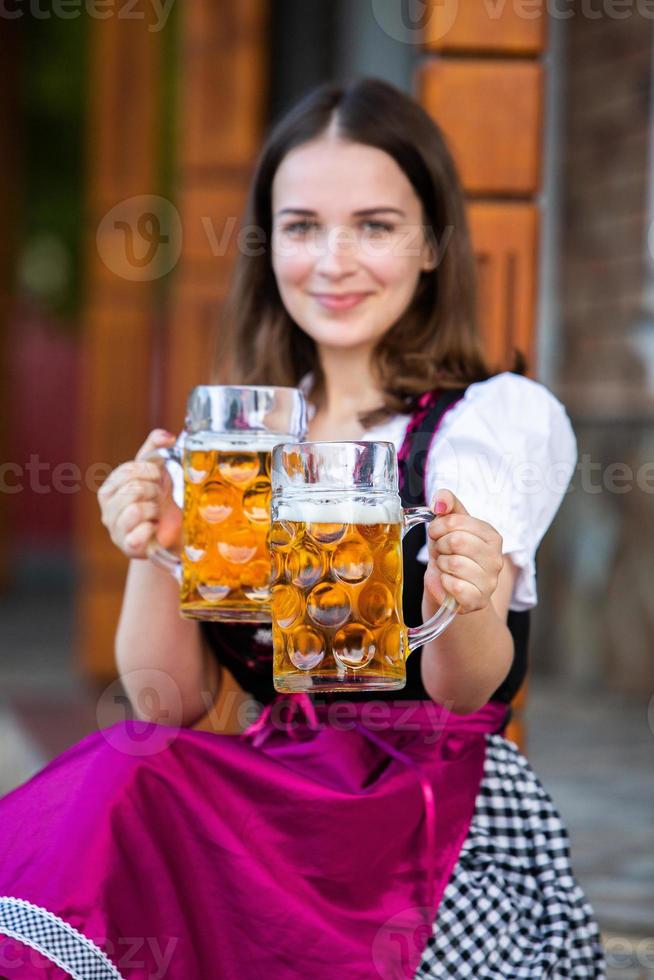donna russa sexy in vestito bavarese che tiene boccali di birra. foto