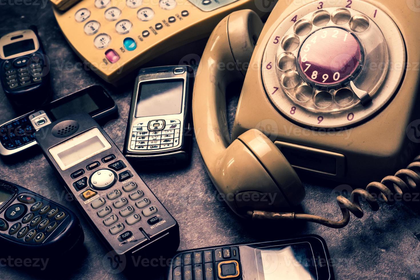 un vecchio telefono con quadrante rotante, linea fissa e cellulare obsoleto su uno sfondo grunge. foto