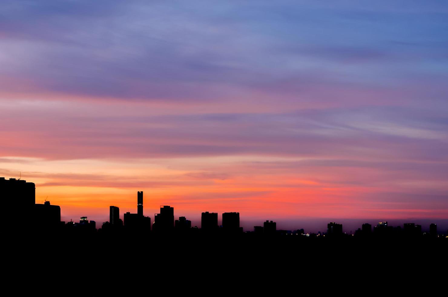 cielo al tramonto colorato in serata con silhouette di molti edifici in città. foto