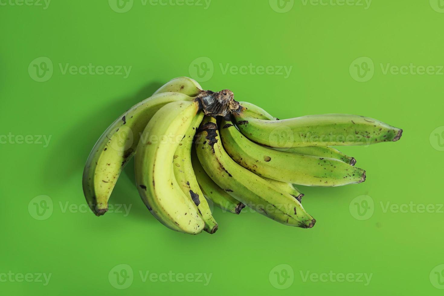 grande mazzo di banane verdi fresche su sfondo verde foto
