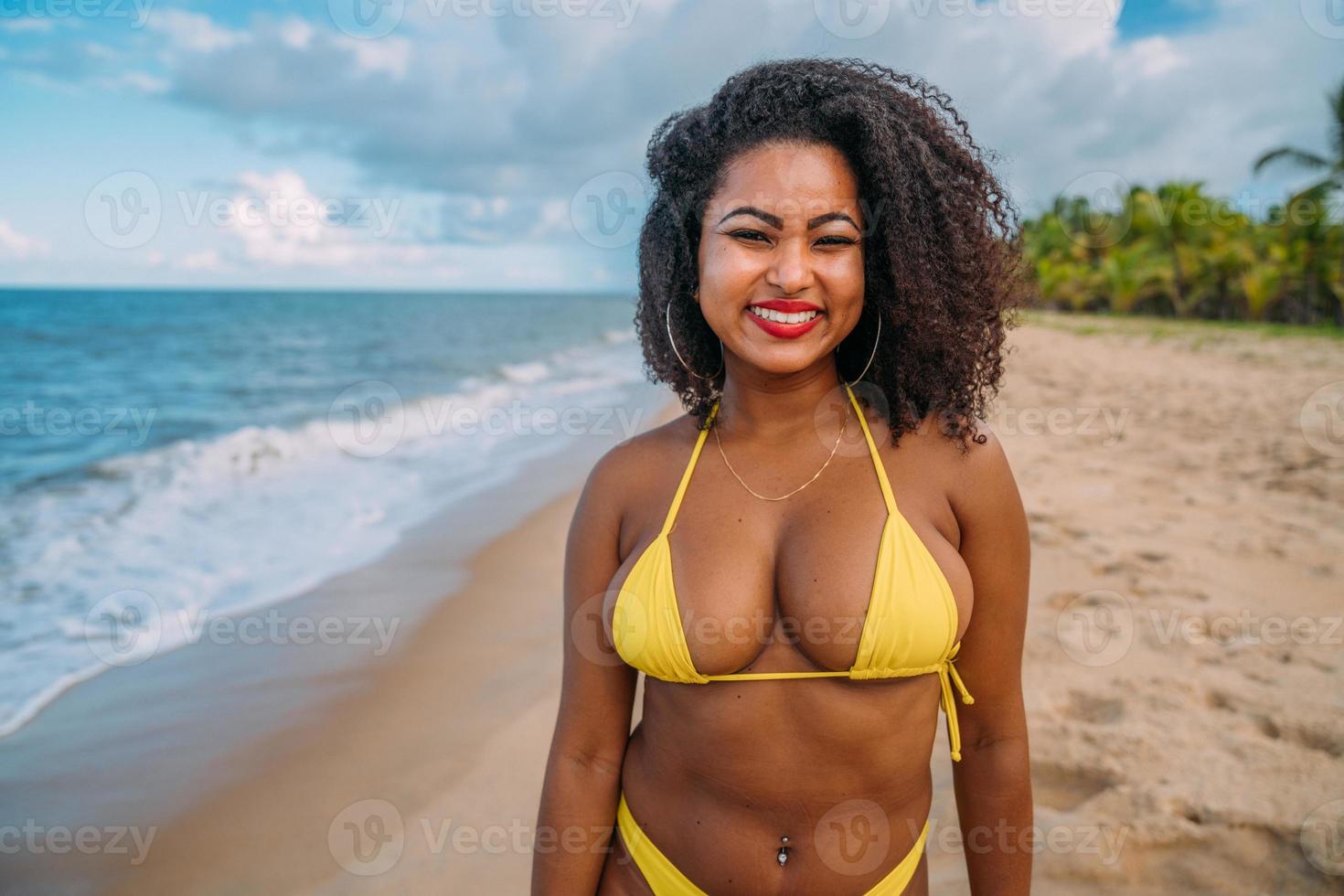 bella donna latinoamericana in bikini sulla spiaggia. giovane donna godendo le sue vacanze estive in una giornata di sole, sorridente e guardando la telecamera foto