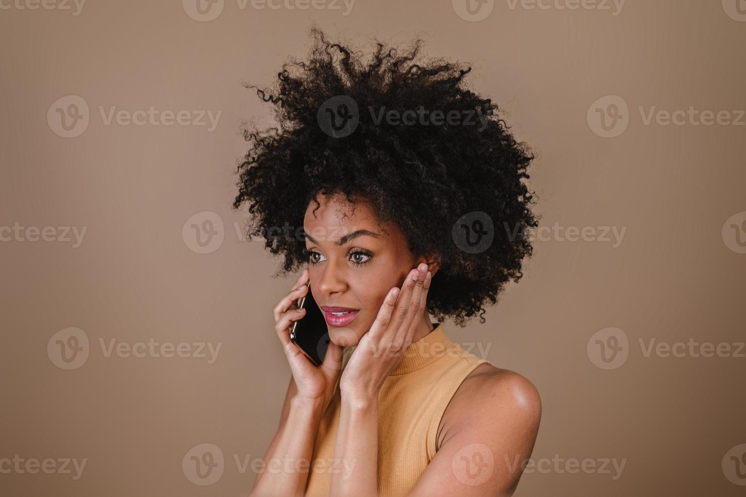 immagine di eccitata giovane donna latina sorpresa utilizzando il cellulare su sfondo pastello. foto