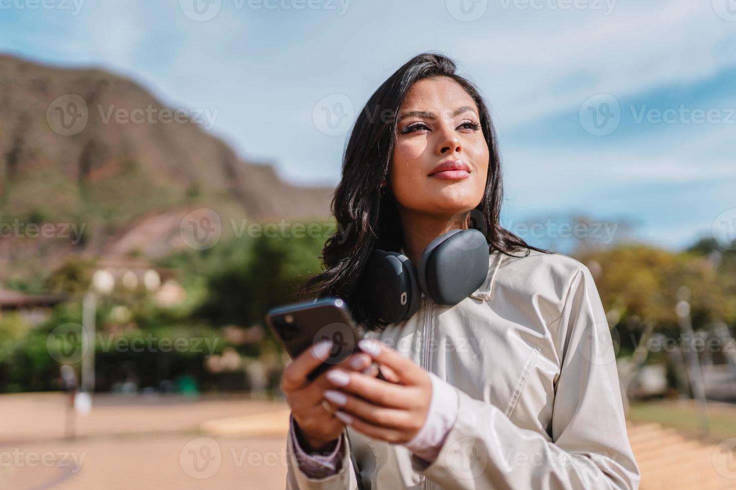 bella ragazza latina che usa il suo telefono cellulare al parco. foto