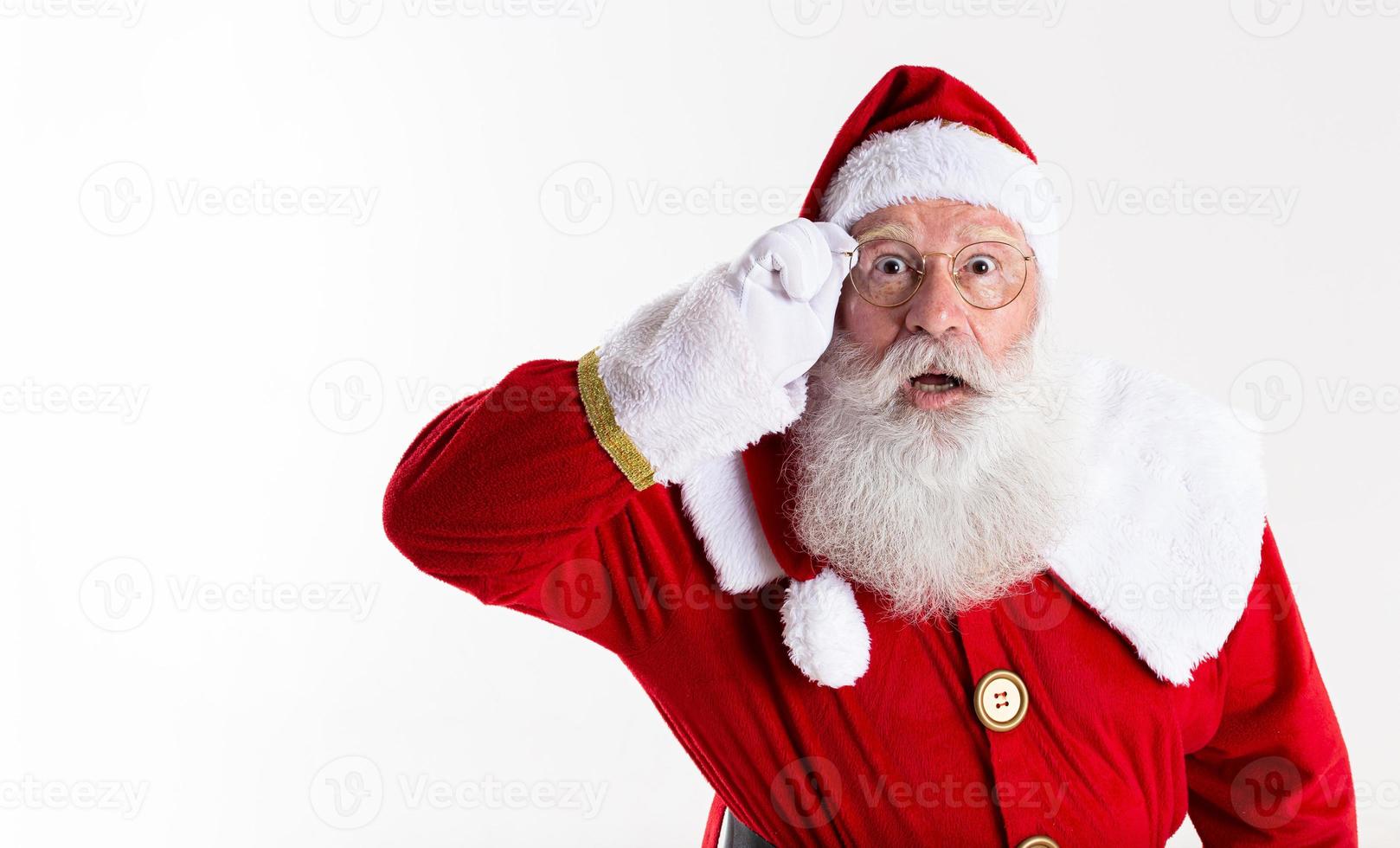 Babbo Natale con gli occhiali sta guardando sorpreso dalla fotocamera su sfondo bianco foto