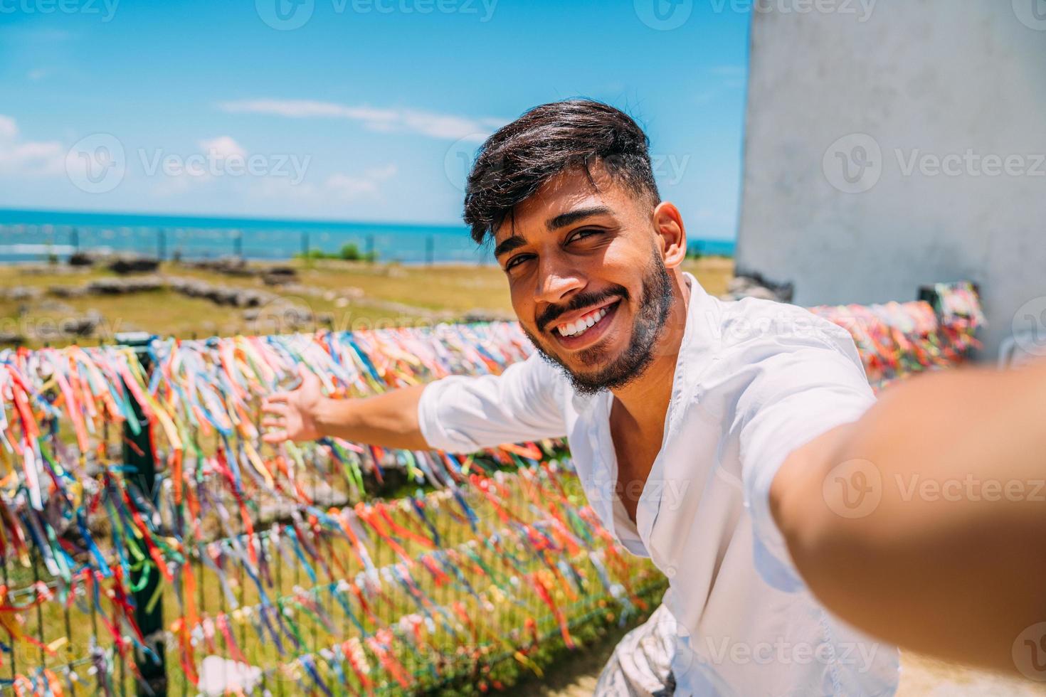 amichevole giovane latinoamericano che invita a venire in brasile, fiducioso e sorridente facendo un gesto con la mano, essendo positivo e amichevole foto