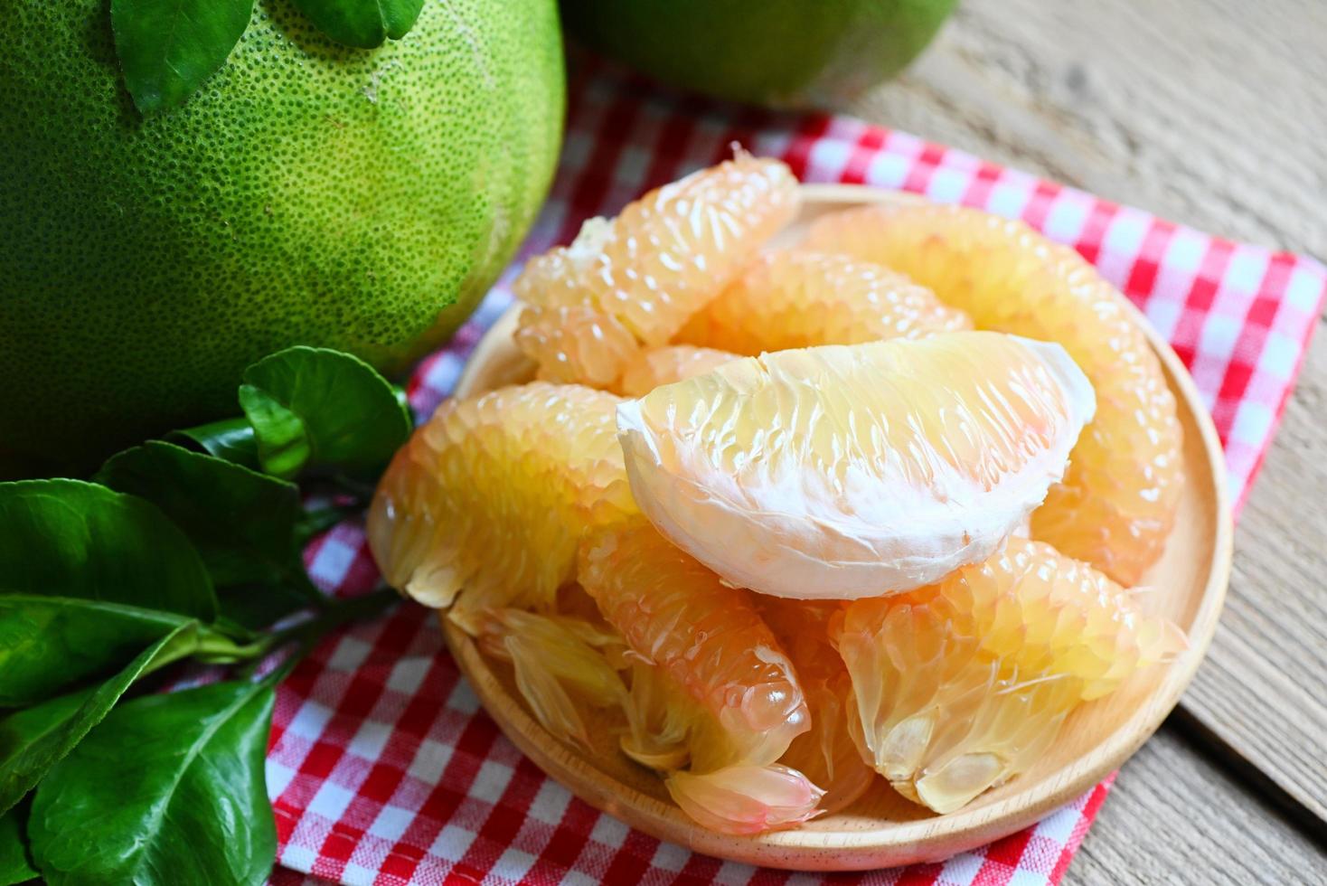 pomelo verde fresco sbucciato e foglia da albero di pomelo, pummelo, pompelmo in estate frutta tropicale in tailandia, pomelo su fondo di piatto di legno foto