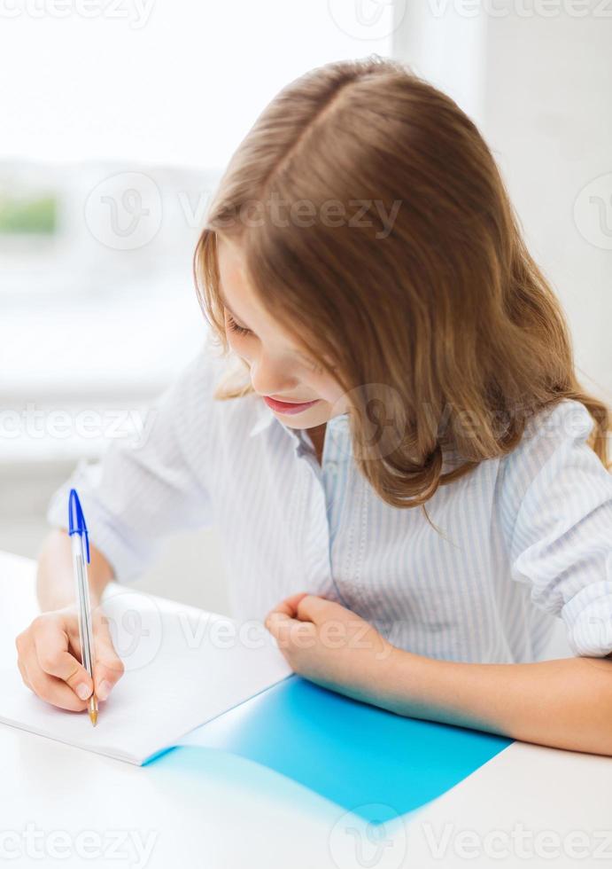 ragazza studentessa scrivendo nel quaderno a scuola foto