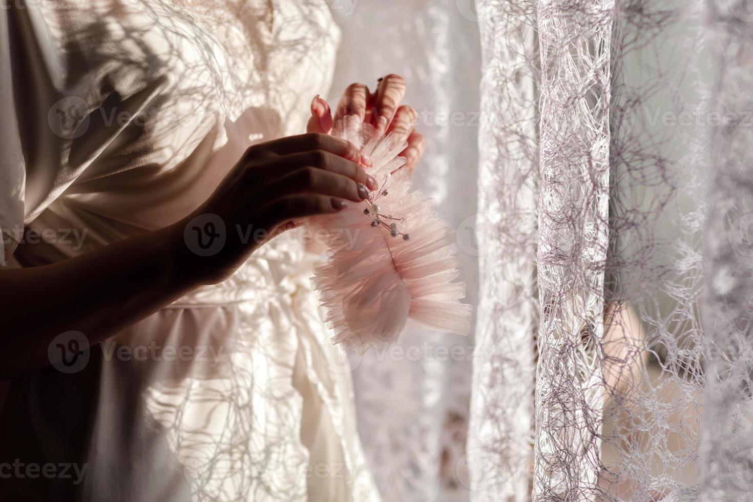 preparazione del mattino della sposa. bella sposa in vestaglia da sposa bianca sullo sfondo della grande finestra della camera da letto. foto di alta qualità