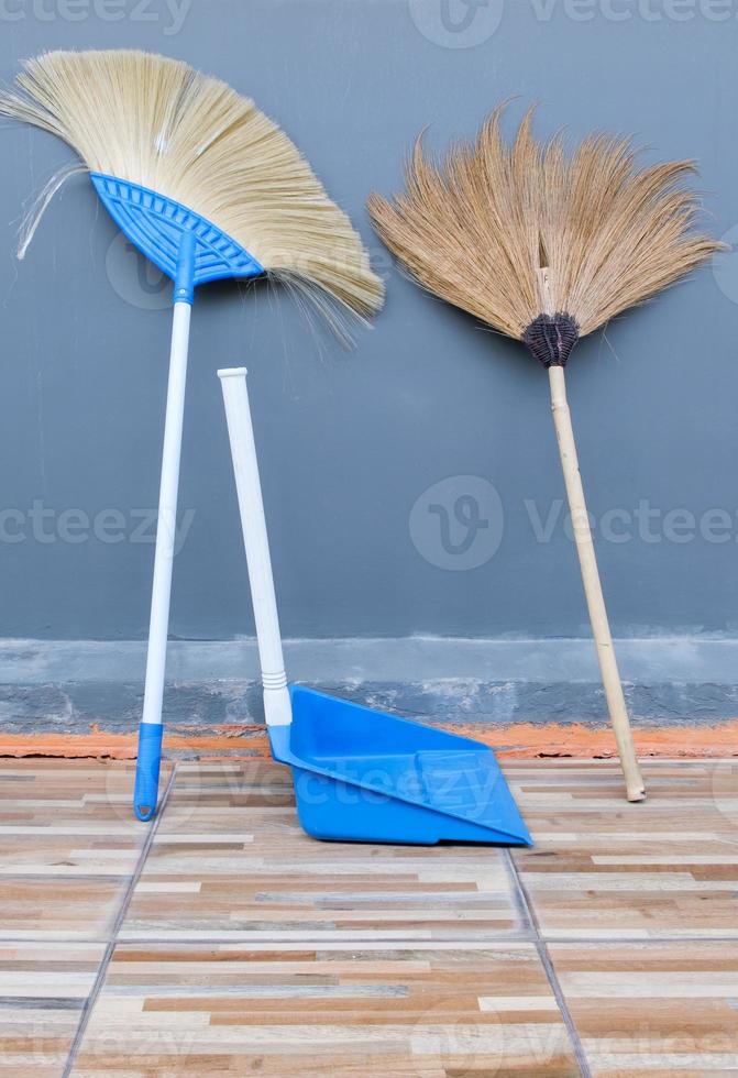 la doppia scopa e la paletta di plastica sono appoggiate al muro laterale della casa. foto