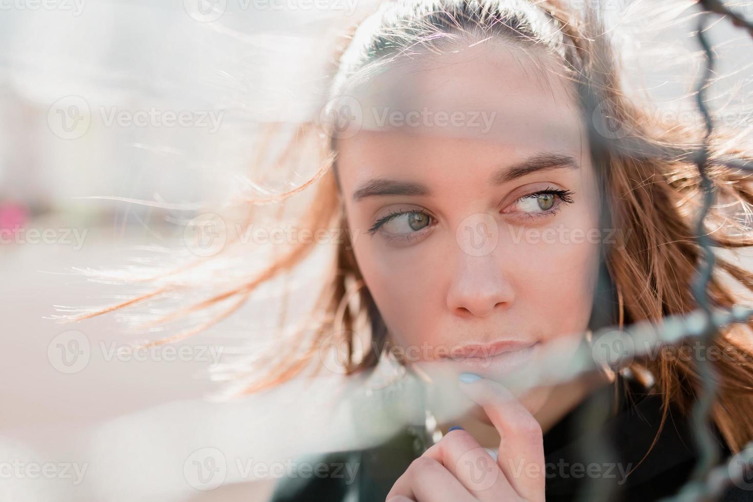 fuori primo piano ritratto di giovane donna attraente con capelli volanti e grandi occhi verdi in una calda giornata di sole foto