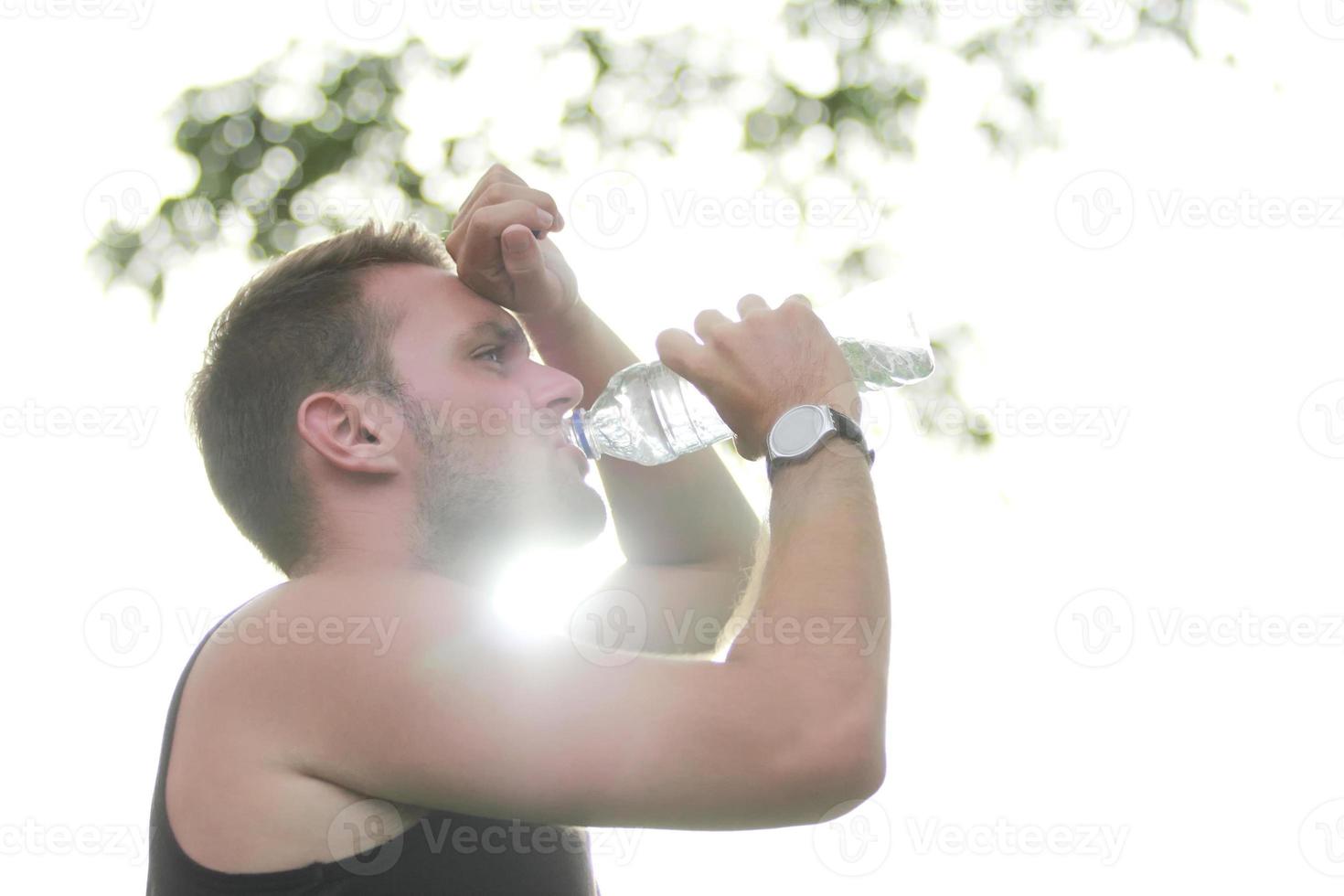 corridore maschio che beve acqua minerale foto