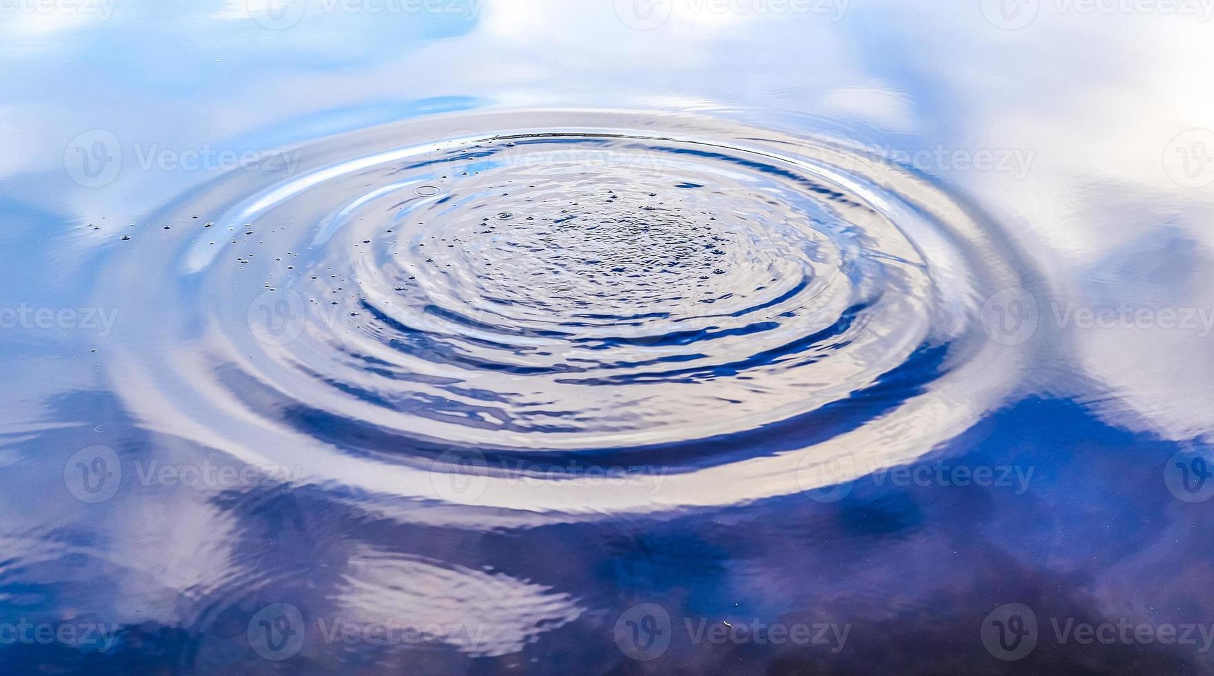 bella acqua in un lago con spruzzi d'acqua e increspature sulla superficie con nuvole e riflessi di cielo blu foto