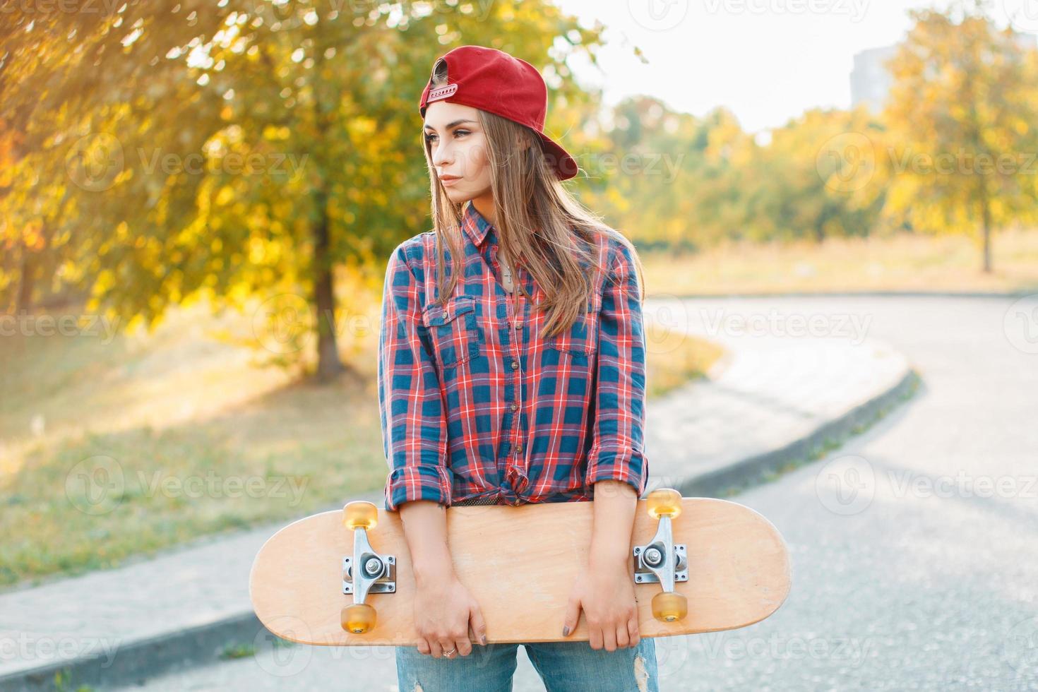 bella e moda giovane donna in posa con uno skateboard foto