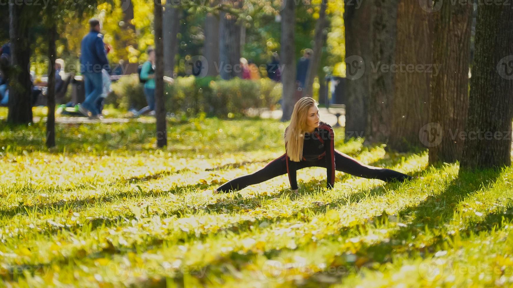 giovane modello femminile fitness che si esercita in un prato al parco autunnale, concetto di attività sportive all'aperto - flessibilità foto