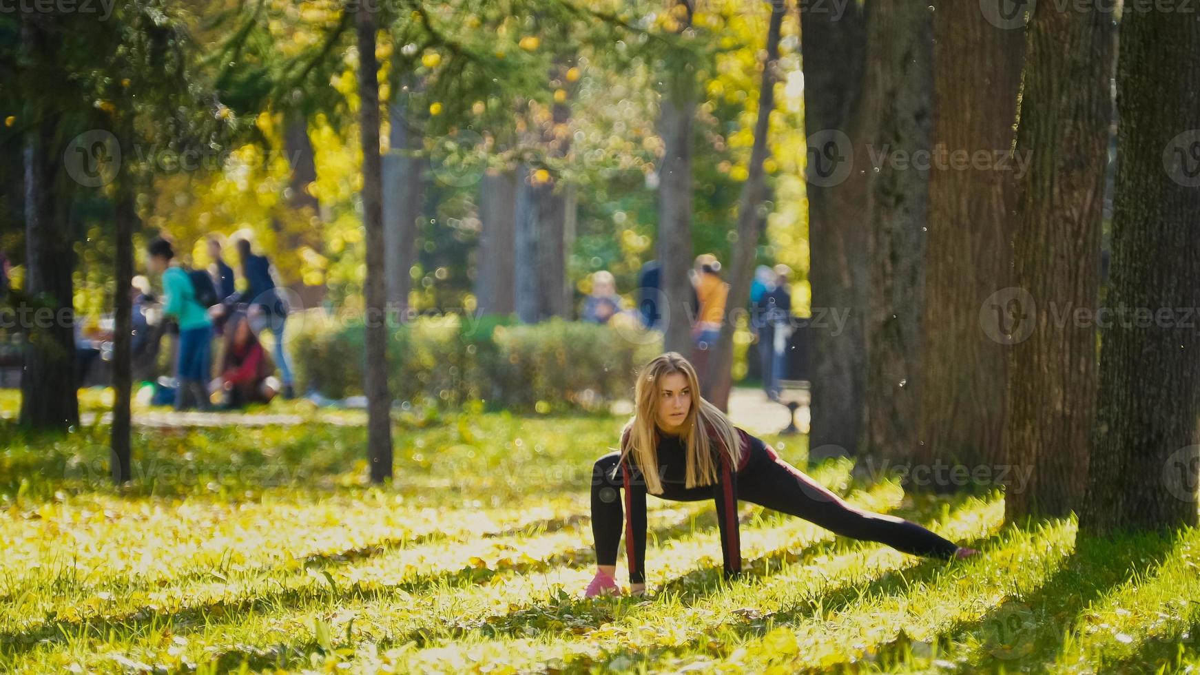 fitness donna forza allenamento facendo allenamento al soleggiato parco autunnale. adatta ragazza sportiva caucasica che esercita il suo corpo foto