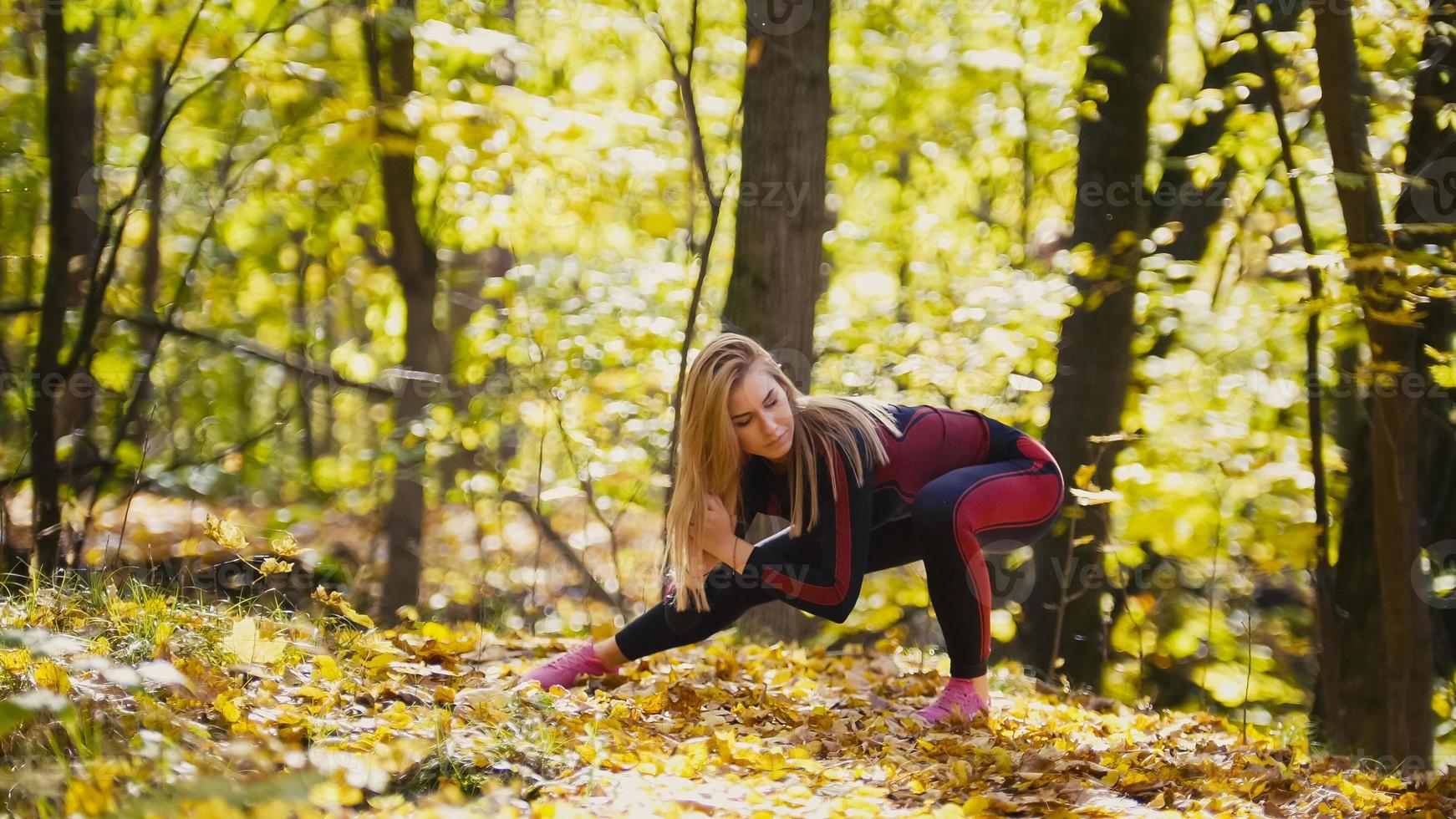 donna che fa esercizi di fitness all'aperto. allungamento femminile nella foresta d'autunno. ragazza magra all'allenamento - squat foto