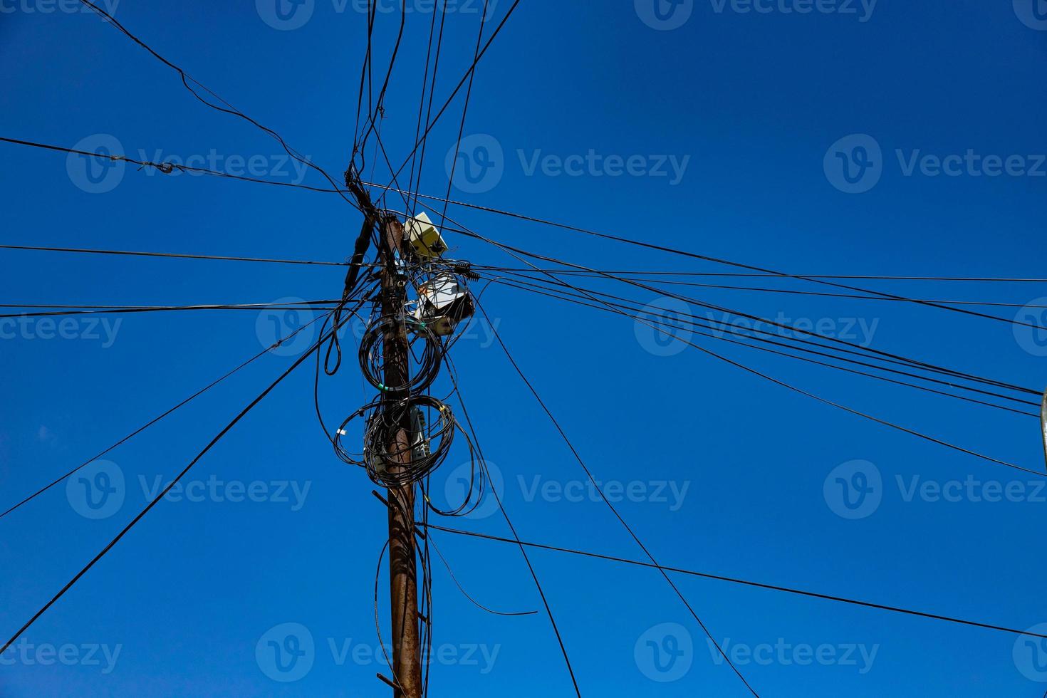 palo stradale con molti fili elettrici e cavi in fibra ottica, cavo in fibra ottica contro il cielo blu. foto