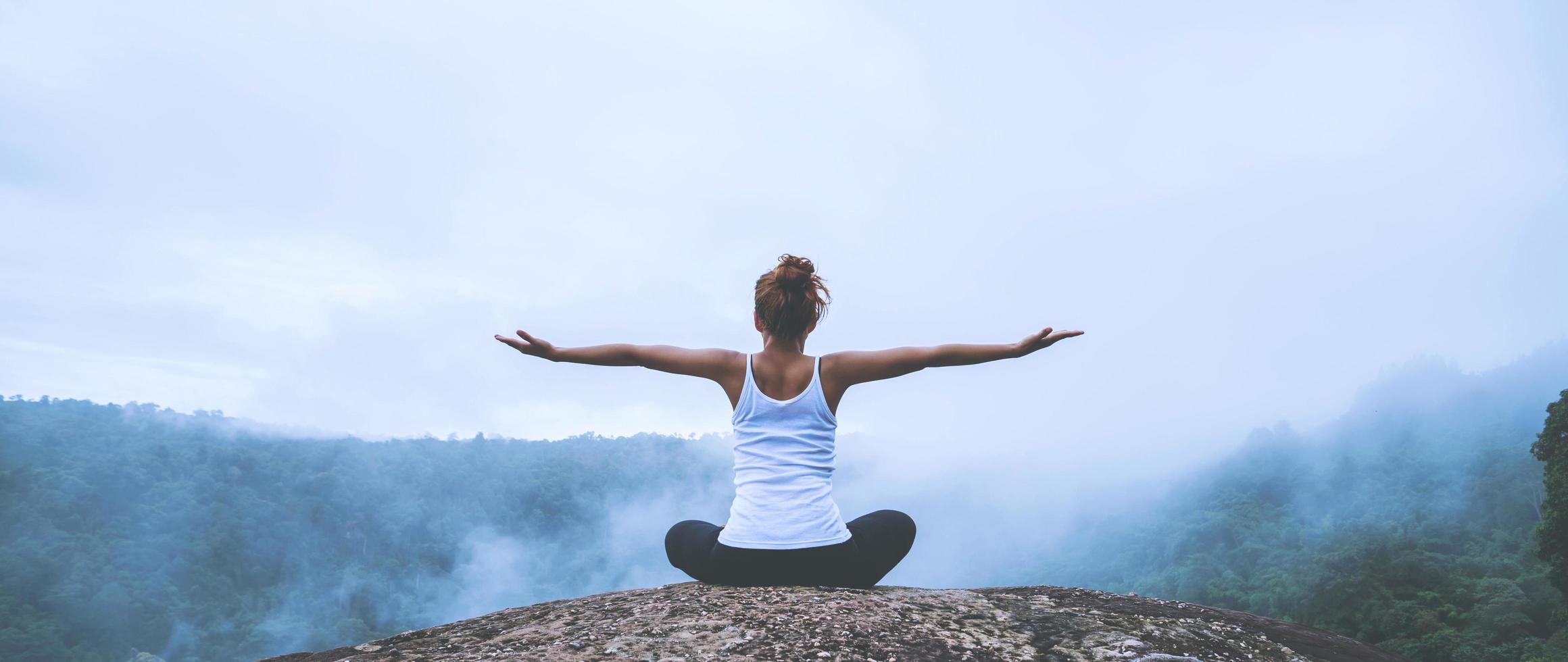 giovane donna esercita yoga in montagna. natura di viaggio donna asiatica. viaggi relax esercizi yoga tocco nebbia naturale sulla vetta della montagna. foto