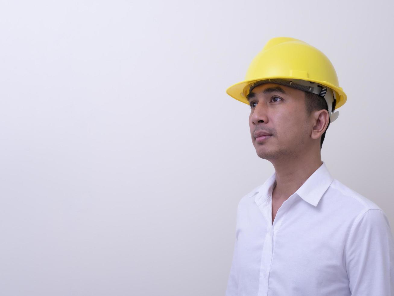 ingegnere con le mani incrociate che indossa il casco giallo su sfondo bianco foto