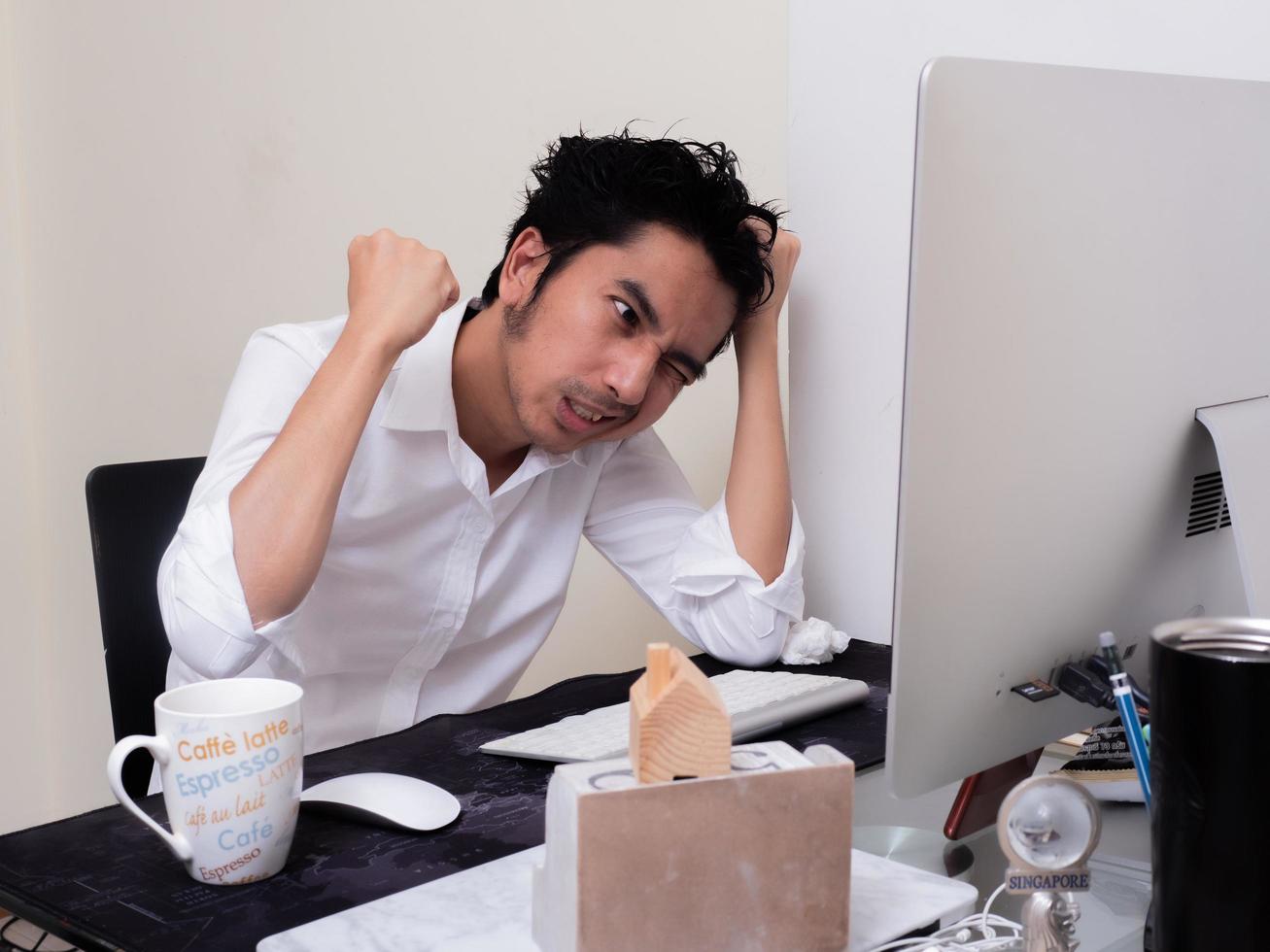 l'uomo asiatico serio sta lavorando con il laptop nella sua camera da letto dell'appartamento nel concetto di lavoro da casa e lavoro a casa foto