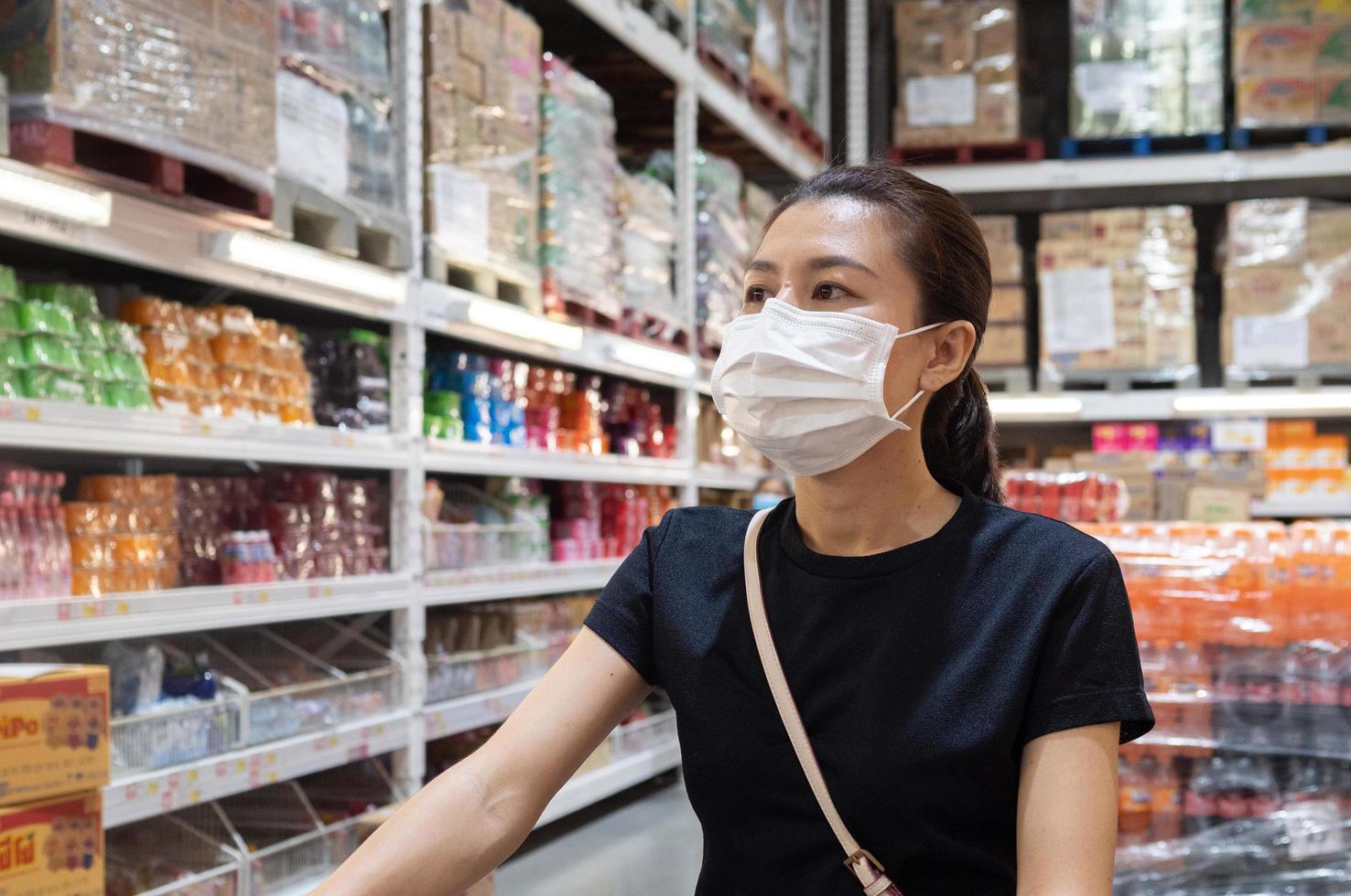 donna che indossa una maschera protettiva monouso per la spesa al supermercato durante l'epidemia di polmonite da coronavirus foto