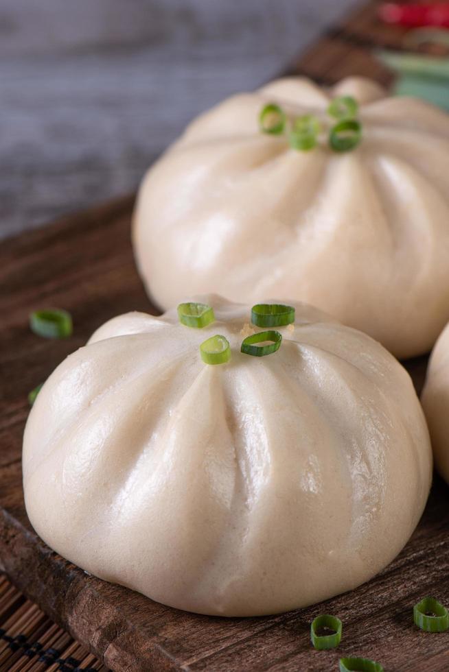 delizioso baozi, il panino cinese di carne al vapore è pronto da mangiare sul piatto da portata e sul piroscafo, primo piano, copia spazio concetto di design del prodotto. foto