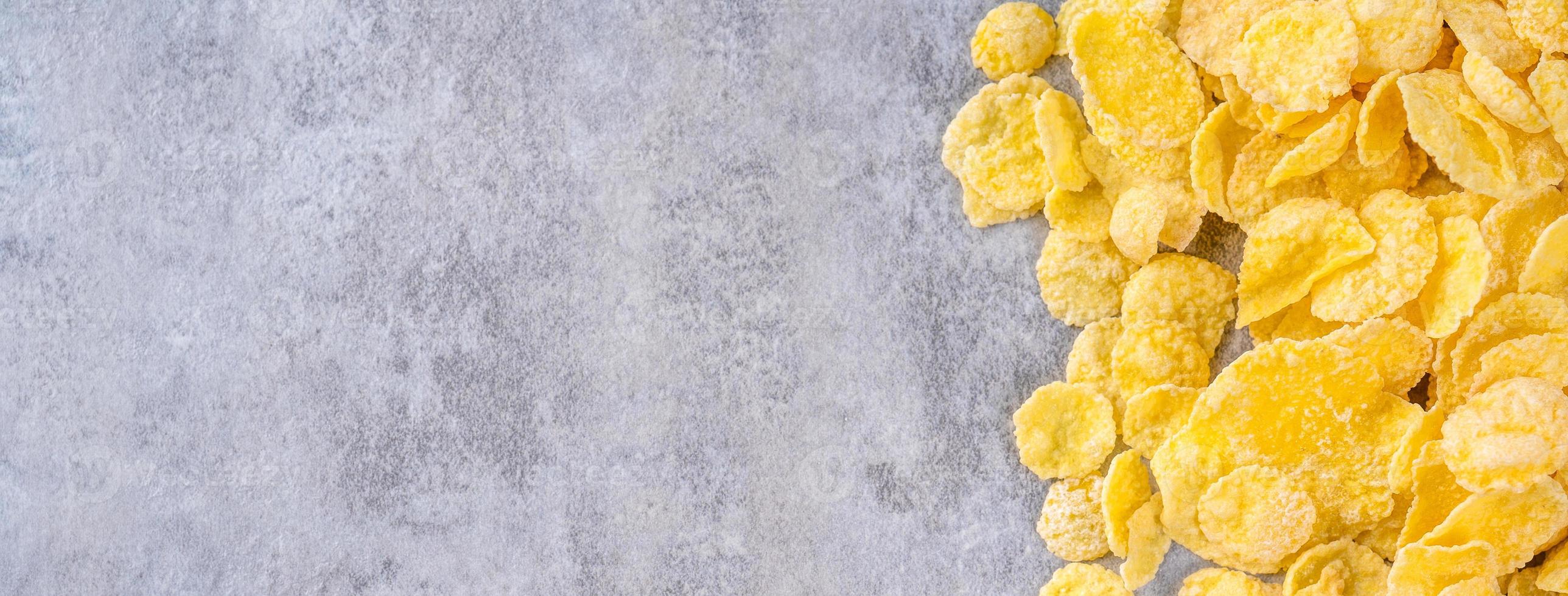 Ciotola di fiocchi di mais dolci su sfondo grigio di cemento, design piatto con vista dall'alto, concetto di colazione fresca e sana. foto