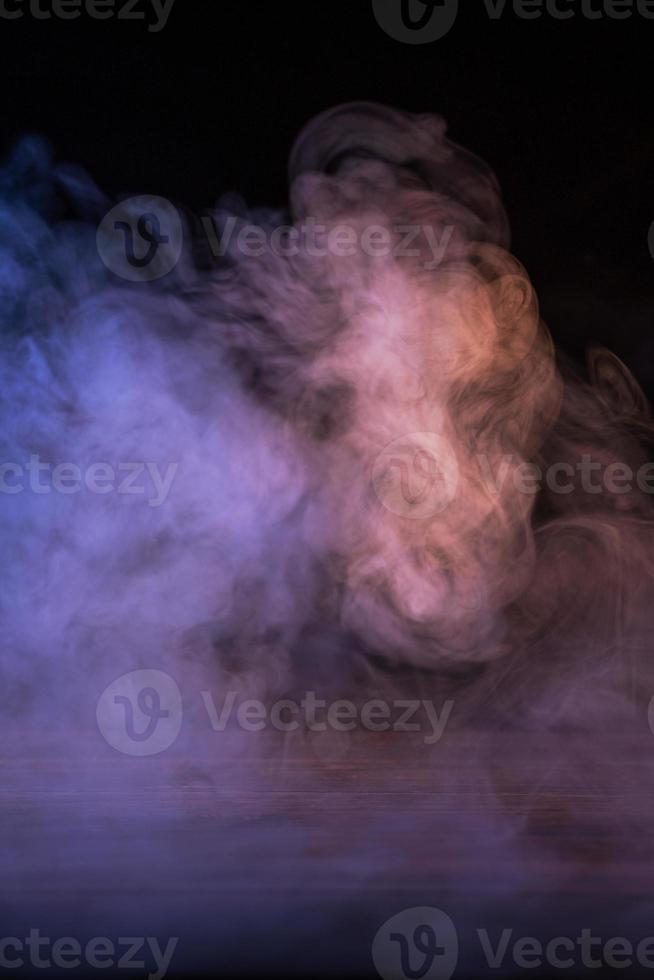 immagine concettuale di fumo multicolore isolato su sfondo nero scuro e tavolo in legno. foto