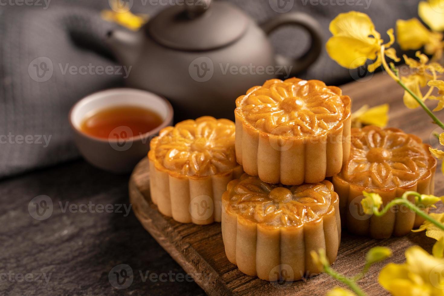 mooncake, torta lunare per il festival di metà autunno, concetto di cibo festivo tradizionale su tavolo in ardesia nera con tè e fiore giallo, primo piano, spazio per la copia. foto