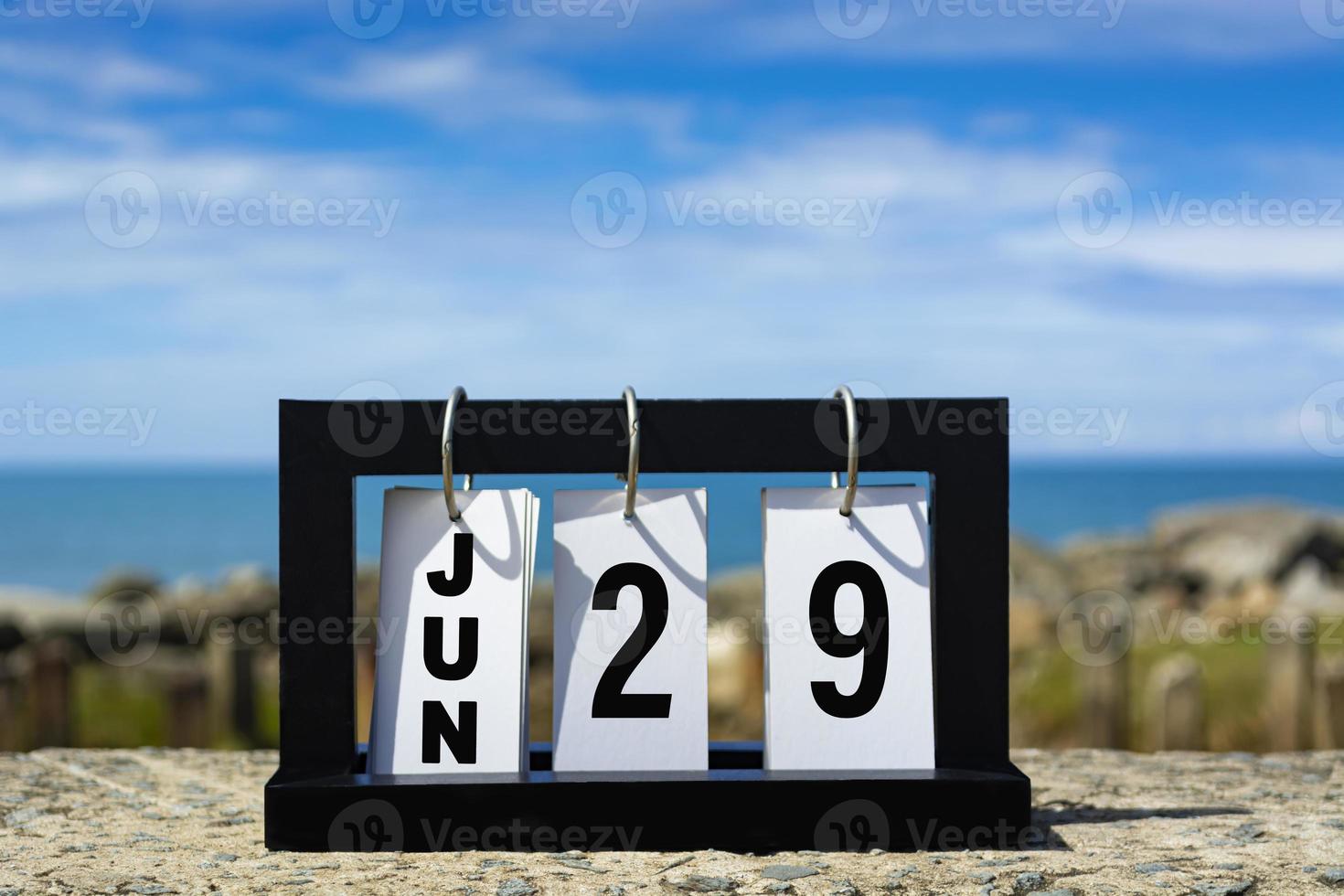 testo della data del calendario su telaio in legno con sfondo sfocato dell'oceano. foto