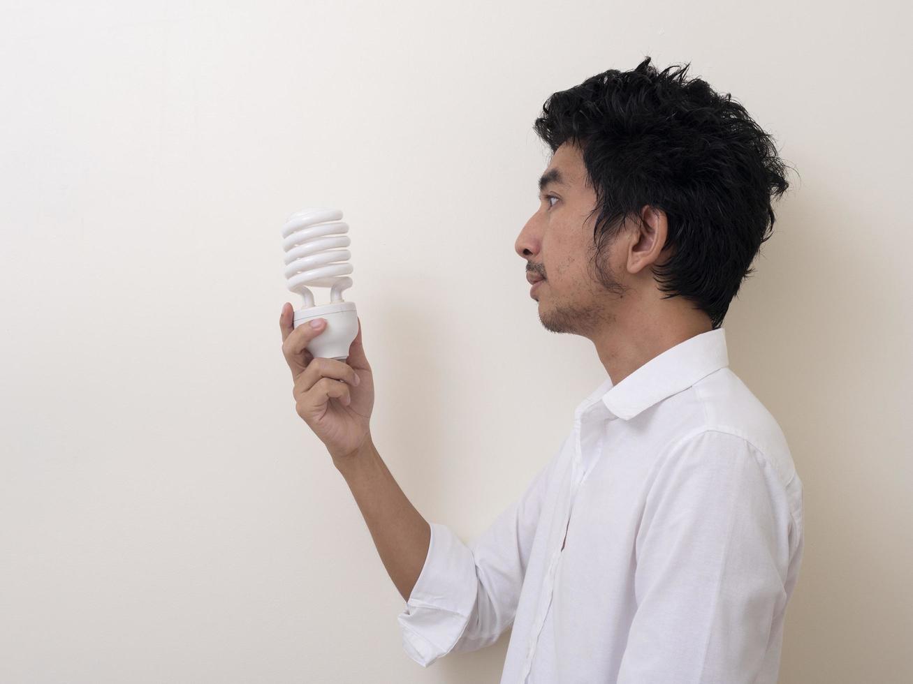 uomo che tiene lampadina a risparmio energetico per lampada foto