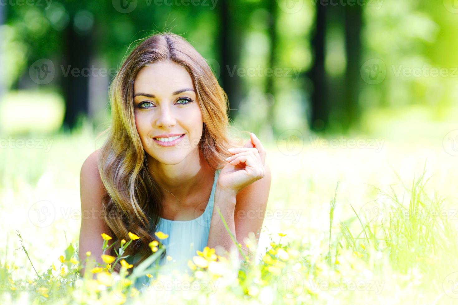 giovane donna in abito blu sdraiato sull'erba foto