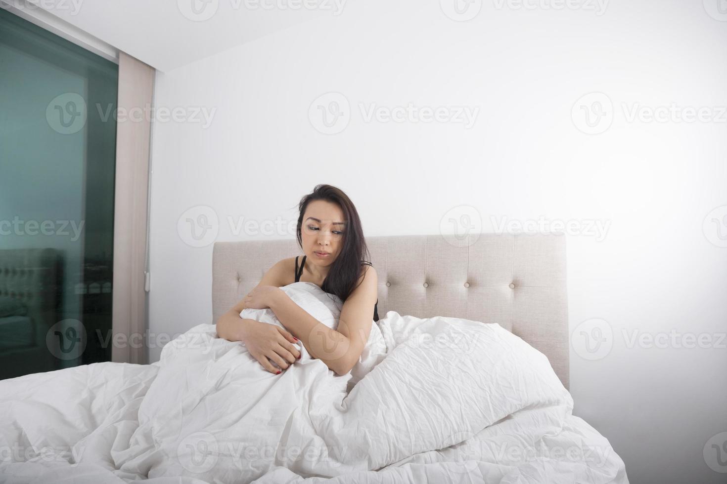 triste giovane donna seduta sul letto foto