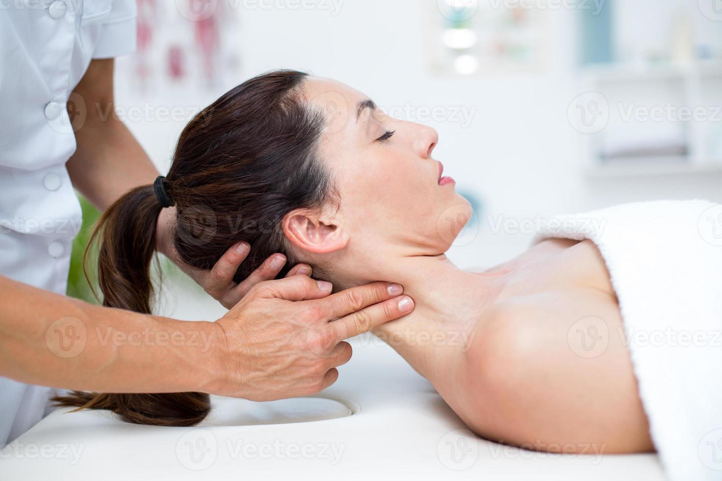 Fisioterapista che fa massaggio al collo foto