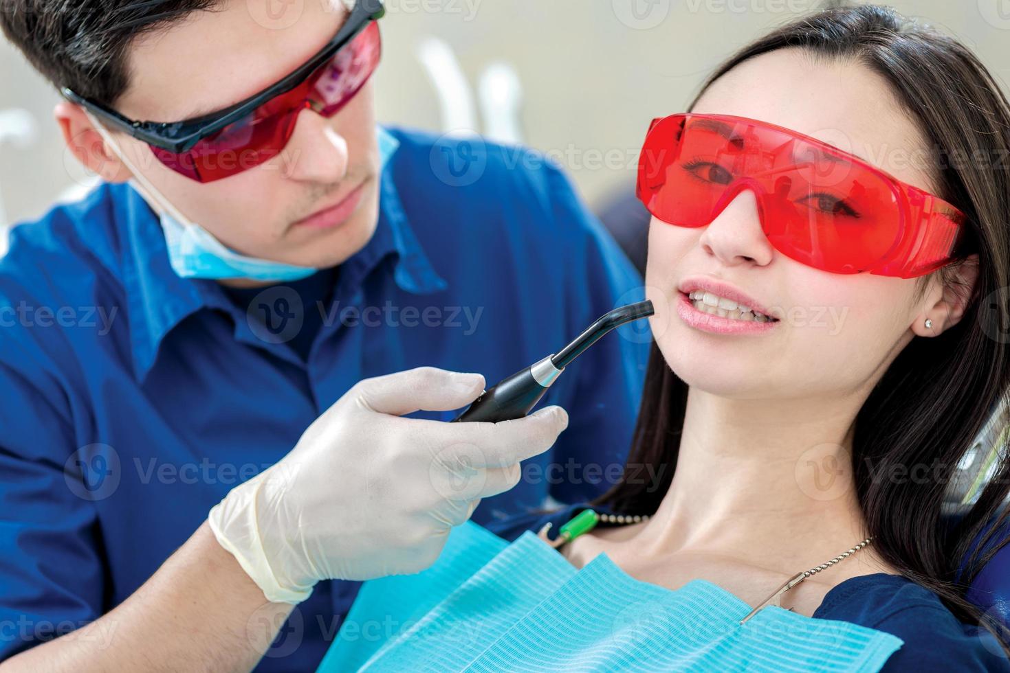 processo dentale. dentista con in mano una lampada a raggi ultravioletti foto