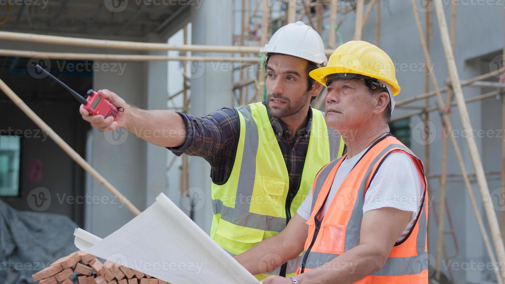 professionista maschio ingegnere civile o architetto, ispettore con appaltatore, caposquadra o lavoratore. mentre guardi il piano del progetto, ispeziona, discuti il progetto di costruzione della riunione e indica il cantiere. foto