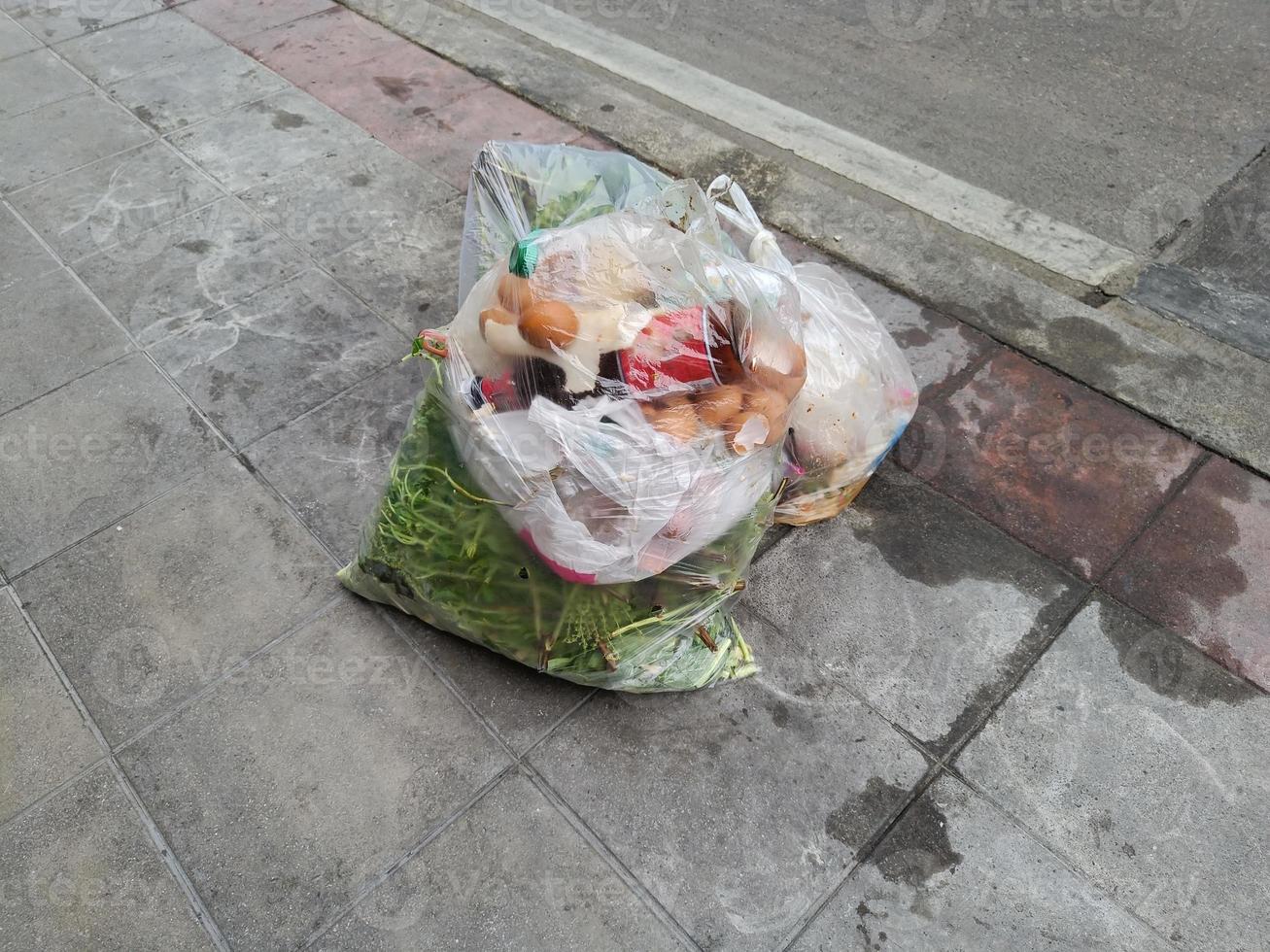 sacchetti della spazzatura di plastica per rifiuti alimentari su una strada lastricata. puzzolente di marcio, malsano per le vie respiratorie. foto