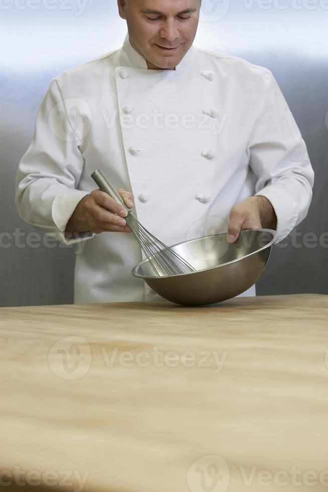 chef maschio mescolando gli ingredienti con la frusta foto